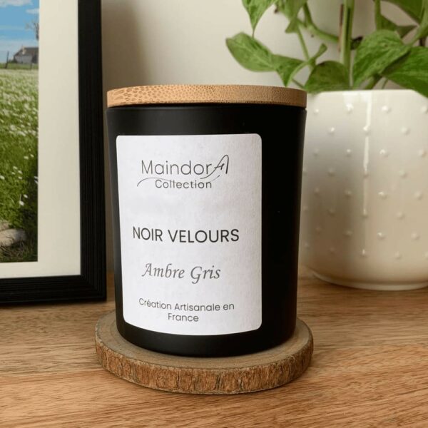 MaindorA Collection : Gros plan sur la bougie parfumée NOIR VELOURS au parfum Ambre Gris dans son écrin noir et couvercle bambou posée sur un meuble en bois naturel de manguier.