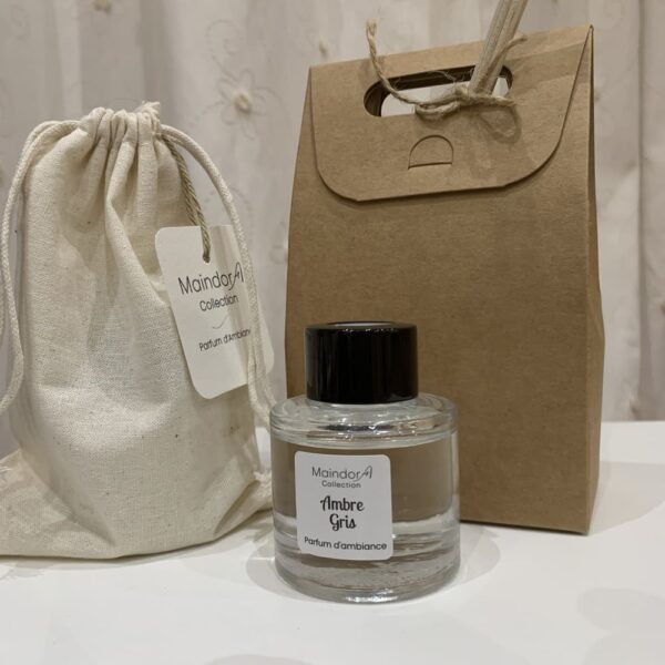 MaindorA- L'ensemble du packaging du modèle Découverte des diffuseurs de parfum d'ambiance est présenté dans cette image. Son pochon en coton écru, sa jolie boite kraft qui se resserre en haut comme une pochette laissant dépasser les bâtonnets de rotin naturel. La senteur proposée est AMBRE GRIS.