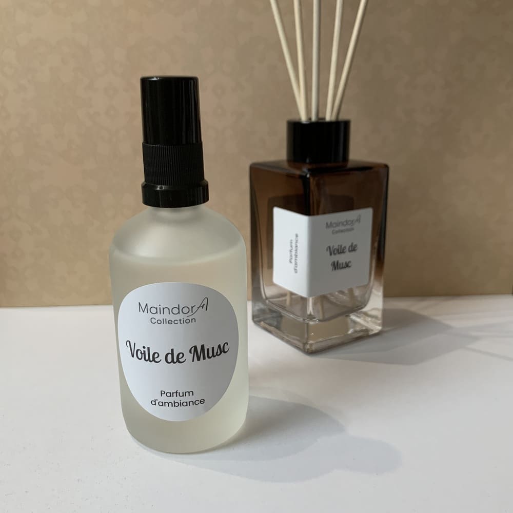 MaindorA-Flacon vaporisateur de parfum d'intérieur avec la senteur VOILE DE MUSC est présenté avec un diffuseur de parfum d'ambiance modèle Singulier ambre fumé, en arrière plan, proposant le même parfum. Ainsi chez MaindorA tout un ensemble de créations parfumées sont réalisées avec la même senteur.