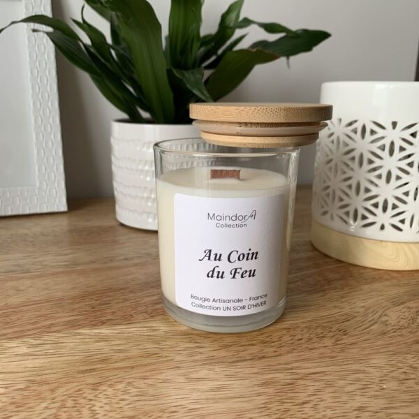 MaindorA-Bougie Parfum "Au Coin Du Feu" avec son couvercle en bambou légèrement posé sur le côté laissant apparaitre la mèche en bois spécificité des bougies de la collection.