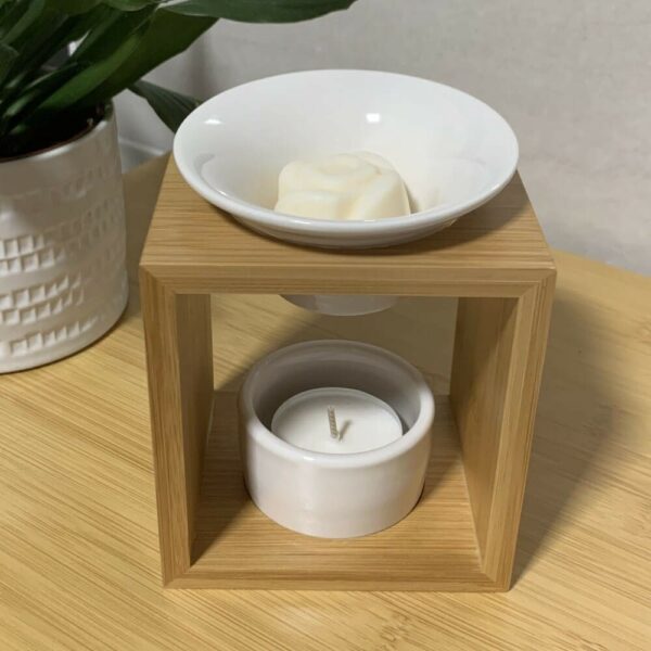 MaindorA-Brûle-parfum support Bambou forme d'une arche avec ses coupelles en céramique blanche. Un fondant de cire de soja sans OGM est posé dans sa coupelle. Une mini bougie réalisée artisanalement est posée dans la coupelle du bas.